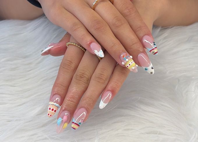 Almond birthday nails with tiny 3D cakes, painted balloons, coloured stones and white French tips, every nail a little different.